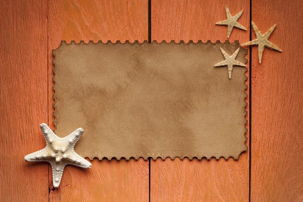 Etiqueta de papel y estrellas de mar sobre fondo de madera — Foto de Stock