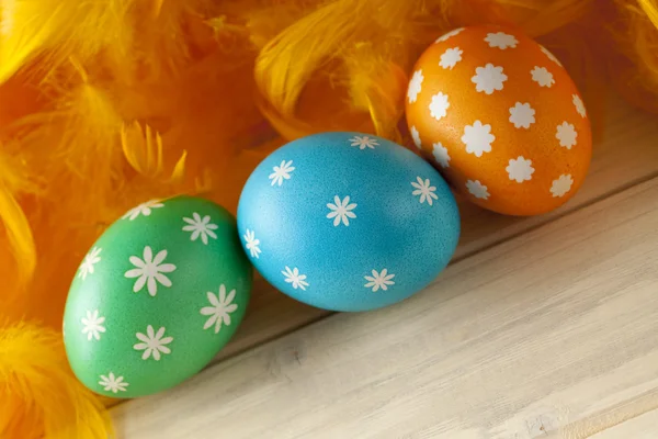 Uova di Pasqua e piume su tavole di legno — Foto Stock