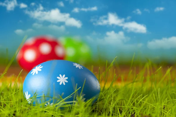 Ovos de Páscoa coloridos na grama e fundo azul do céu — Fotografia de Stock