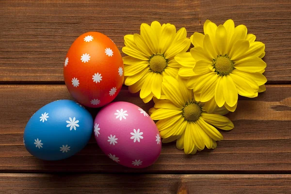 Uova di Pasqua colorate e fiori su sfondo di legno — Foto Stock