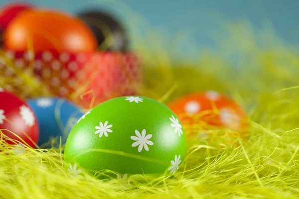 Huevos de Pascua de colores sobre la hierba y el fondo azul del cielo — Foto de Stock