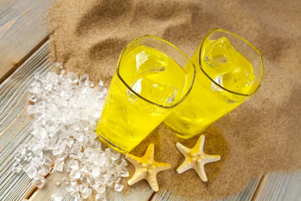 Bebidas frias, conchas e cubos de gelo na praia — Fotografia de Stock