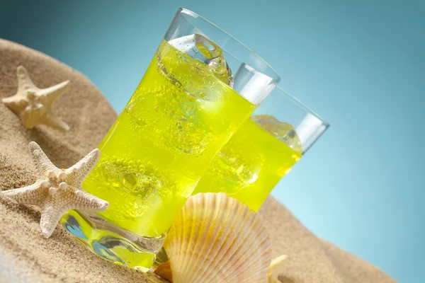 Bebidas frias na praia e fundo azul — Fotografia de Stock