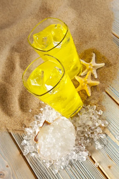 Bebidas frias, conchas e cubos de gelo na praia — Fotografia de Stock