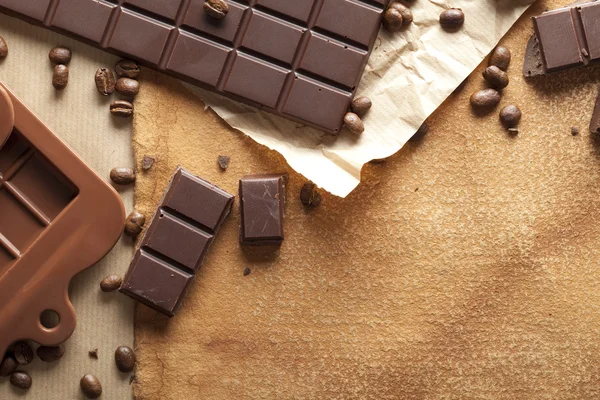 Chocolate negro y granos de café sobre fondo de papel viejo —  Fotos de Stock