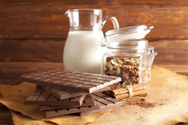Cioccolato, brocca di latte, cannella, cacao e noci miste in un barattolo — Foto Stock