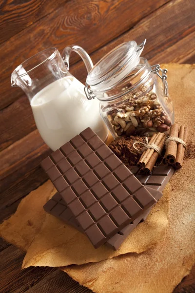 Chocolate ao leite, cacau, paus de canela e nozes em um frasco — Fotografia de Stock