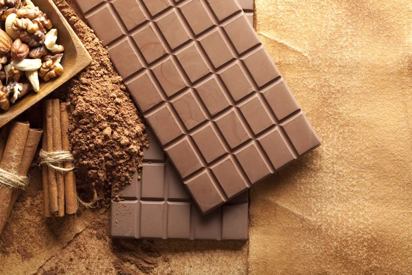 Cuatro barras de chocolate, palitos de canela, cacao y nueces mezcladas en un —  Fotos de Stock