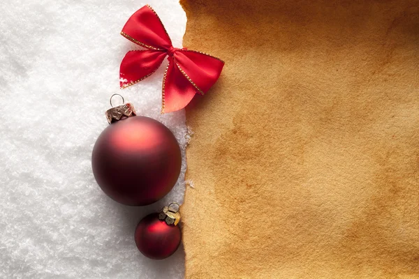 Christmas background - paper sheet and baubles on snow — Stock Photo, Image