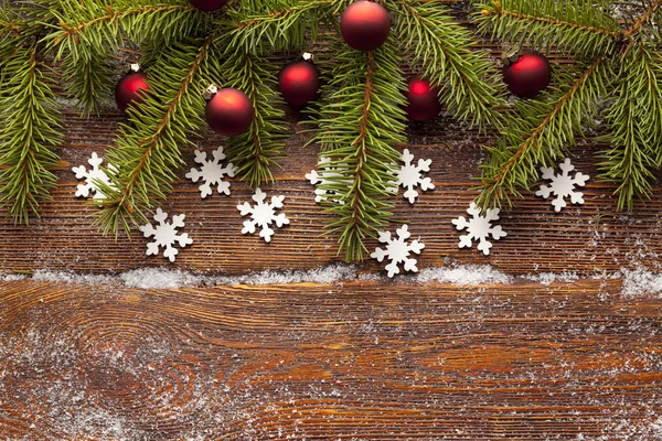Υποκατάστημα του χριστουγεννιάτικο δέντρο, κόκκινα στολίδια και νιφάδες χιονιού σε ξύλινα β — Φωτογραφία Αρχείου