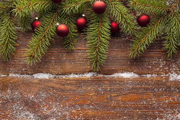 Branch of Christmas tree and baubles on wooden background — Stock Photo, Image