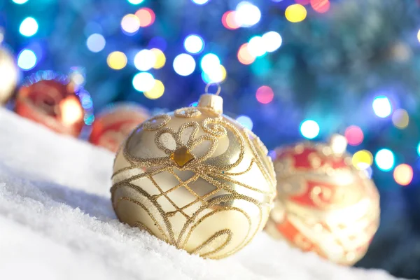 Kerstballen op sneeuw en verlichting achtergrond — Stockfoto