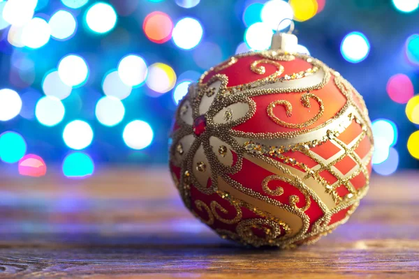 Bugiganga de Natal vermelho na placa de madeira e iluminação de fundo — Fotografia de Stock