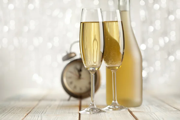 Copos de champanhe e despertador em fundo prateado — Fotografia de Stock