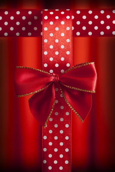 Red bow and patterned ribbon on red abstract background — Stock Photo, Image