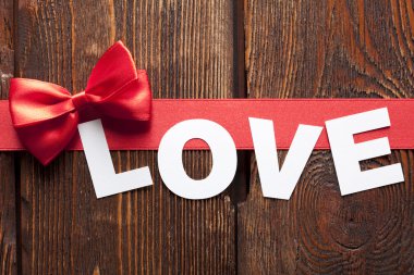 Yazıt sevgi ve ahşap arka plan üzerinde kırmızı kurdele