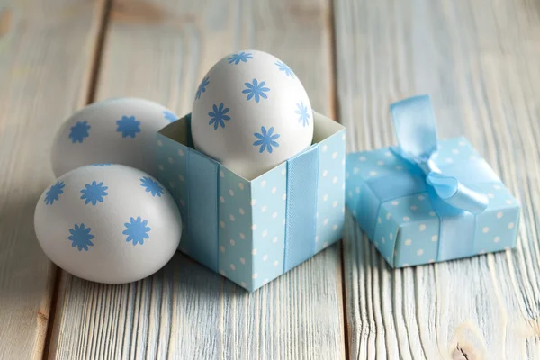 Uova di Pasqua e scatola regalo su sfondo di legno — Foto Stock