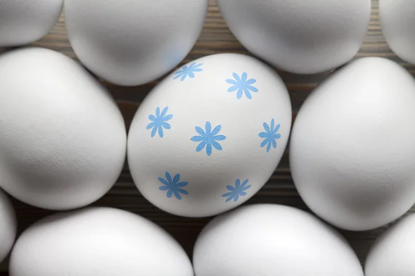 Un uovo con motivo blu e molte uova bianche — Foto Stock