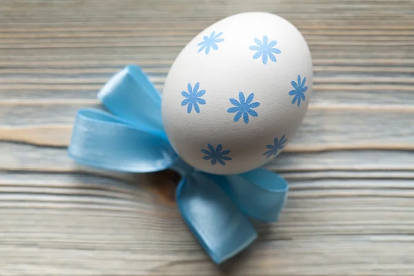 Jeden vzorovaný velikonoční vajíčko a modré luk na dřevěné pozadí — Stock fotografie