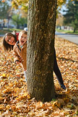 Anne ve oğlu sonbahar yürüyüşünde gülüp oynuyorlar. Mutlu bir aile.