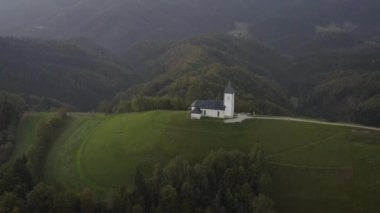 Slovenya 'da bir tepenin üstündeki güzel bir kilisenin sonbahar hava manzarası