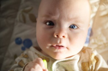 Bebek portresi. Mavi gözlü, yakından bakan yüz.