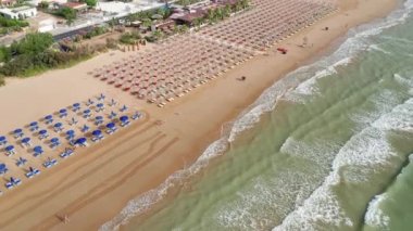 Gün batımında renkli şemsiyeli ve turkuaz deniz manzaralı harika bir sahil manzarası. Akdeniz, Vieste, İtalya