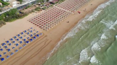 Gün batımında renkli şemsiyeli ve turkuaz deniz manzaralı harika bir sahil manzarası. Akdeniz, Vieste, İtalya