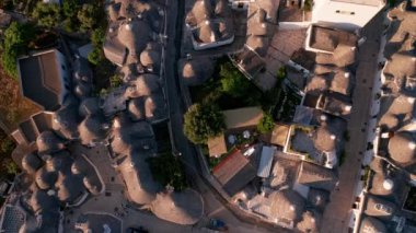 İtalya 'daki Alberobello kasabasının hava manzarası. İnsansız hava aracı güneş doğarken eski kasaba binalarının üzerinde uçuyor.