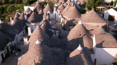 İtalya 'daki Alberobello kasabasının hava manzarası. İnsansız hava aracı güneş doğarken eski kasaba binalarının üzerinde uçuyor.