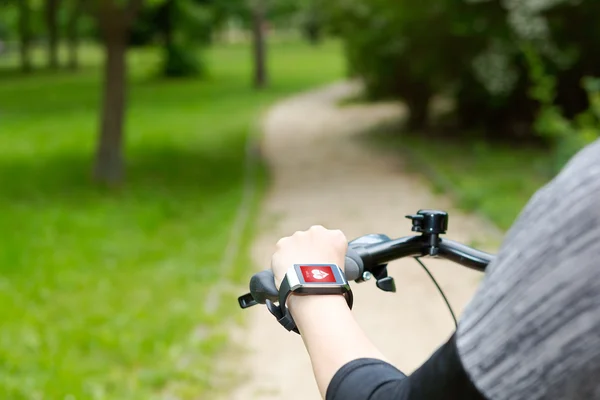 Woman riding a bike with a smartwatch heart rate monitor. — Stock Photo, Image