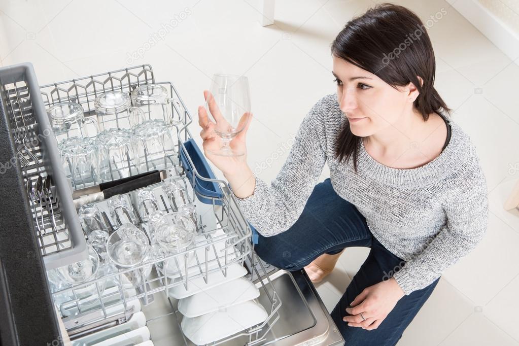 Woman using a dishwasher in a modern kitchen.