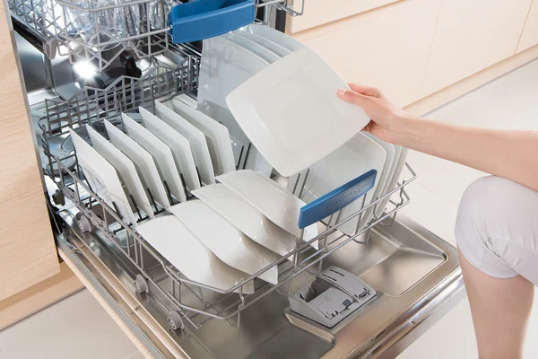 Mujer usando un lavavajillas en una cocina moderna . — Foto de Stock