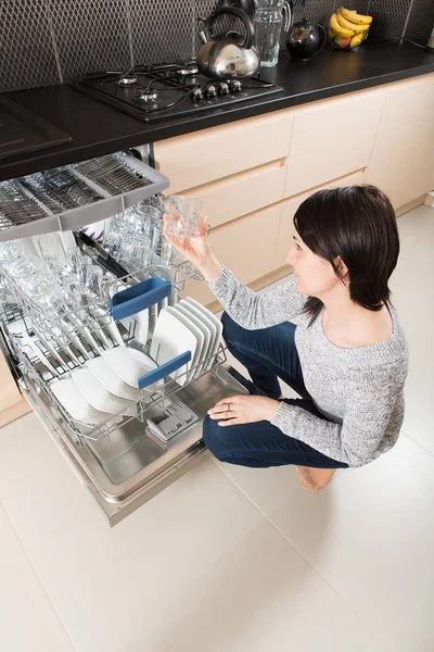 Vrouw met behulp van een vaatwasser in een moderne keuken. — Stockfoto