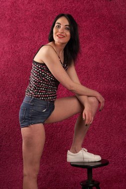                              Güzel esmer poz, pembe arka planda stüdyo oturumu.  