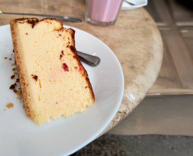 Polonya 'da geleneksel adı Sernik olan bol kremalı cheesecake diliminin yakın çekimi parlak beyaz bir porselen tabakta servis edildi. Tatlıda altın-kahverengi bir kabuk ve hafif, küçük görünen kırıntılar veya meyveli meyveli meyveler yer.