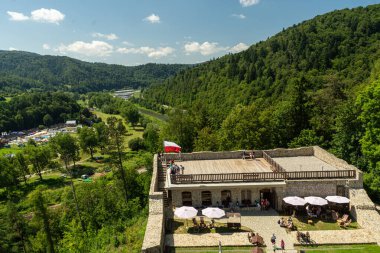 Muszyna, Malopolska Voyvodeship, Polonya - 05 Ağustos 2025 - kısmen yeniden inşa edilmiş Muszyna Kalesi kalıntıları, Poprad nehir vadisi ve Beskid Sadecki ormanlı tepeleri.