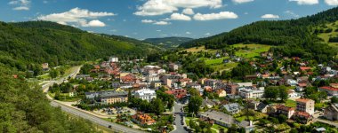 Muszyna, Malopolska Voyvodeship, Polonya - 05 Ağustos 2025 - Yoğun dağ ormanları ve ana yol ile çevrili Poprad nehir vadisinde yer alan Muszyna şehir merkezinin panoramik manzarası.