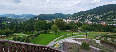 Muszyna, Malopolska Voyvodeship, Polonya - 08 Ağustos 2025 - Duyusal Bahçeler 'deki dairesel çit labirenti manzarası yükseldi ve arka planda orman tepeleri yer aldı..