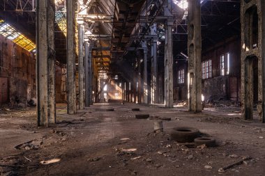 Beton döküntüleri ve hasarlı iç döküntüleriyle terk edilmiş sanayi salonunun geniş görüşü.
