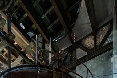 Terk edilmiş kazan dairesinin içinde büyük paslı metal tanklar ve dar servis yolları var..
