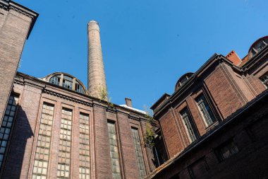 Etrafı tuğla fabrikaları ve uzun bacalarla çevrili eski bir sanayi avlusunun içine bak.