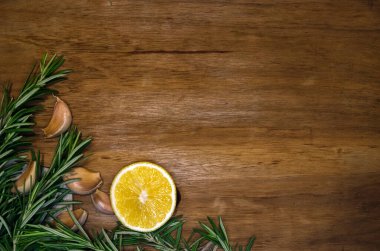 Taze biberiye filizi, sarımsak karanfili ve limon yarısı koyu tahta, kartpostal ya da davetiye şablonu.