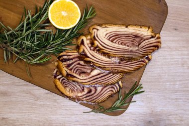 Tatlı tatlı dilimlenmiş hamur işi ve limon ile ahşap bir tahtada servis edilir yarı süslenmiş biberiye filizi ile. 