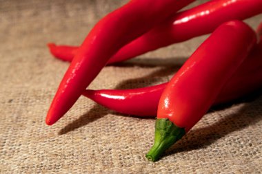 Birkaç parlak kırmızı kırmızı kırmızı biber, kaba bir çuval bezine sarılır.