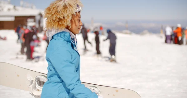 Uśmiechnięta młoda kobieta niosąc snowboard — Zdjęcie stockowe