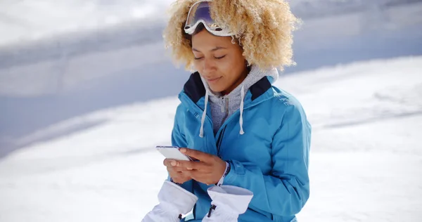 Женщина сидит на снежном берегу и пишет смс — стоковое фото