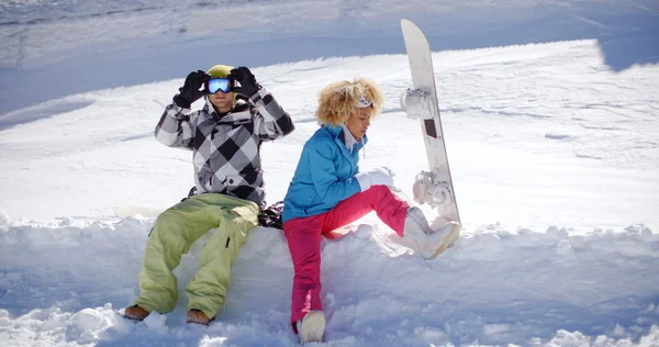 Couple sitting on deep shelf of snow — Stock Photo, Image