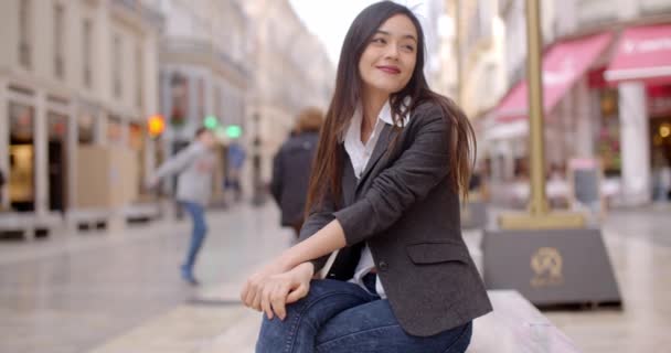 Женщина сидит на скамейке в городе — стоковое видео