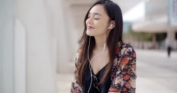 Frau zu Fuß und hört Musik über Kopfhörer — Stockvideo